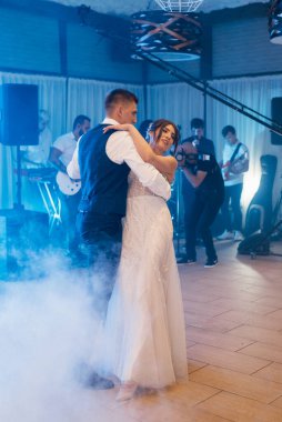 the first dance of the bride and groom inside a restaurant with heavy smoke
