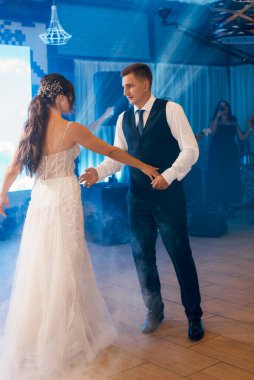 the first dance of the bride and groom inside a restaurant with heavy smoke