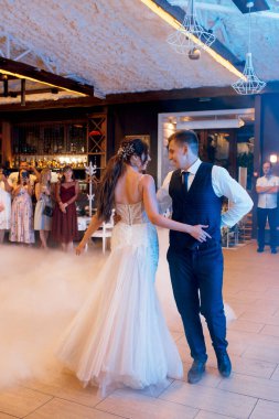 the first dance of the bride and groom inside a restaurant with heavy smoke