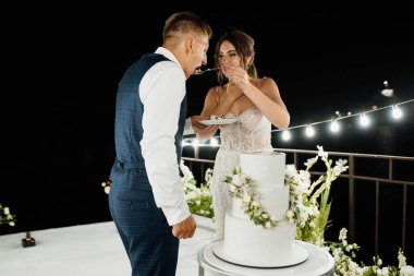 newlyweds happily cut, laugh and taste the wedding cake