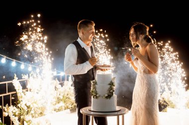 newlyweds happily cut, laugh and taste the wedding cake