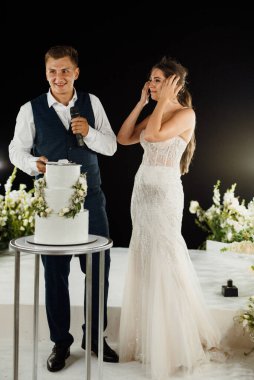 newlyweds happily cut, laugh and taste the wedding cake