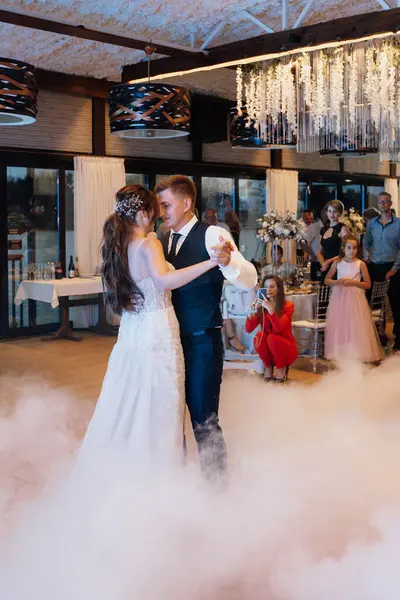 the first dance of the bride and groom inside a restaurant with heavy smoke