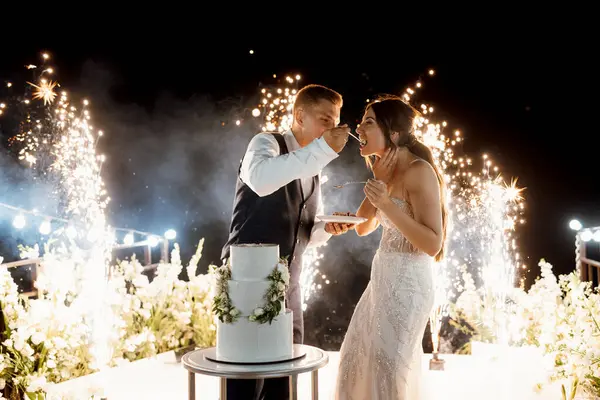 newlyweds happily cut, laugh and taste the wedding cake