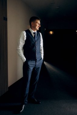 Düğün günü otelde kravatlı, mavi takım elbiseli bir damat portresi.