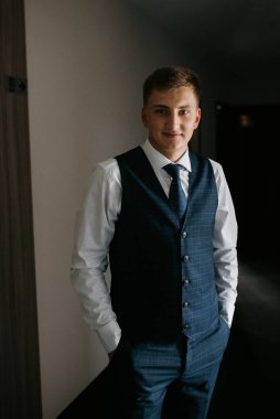 Düğün günü otelde kravatlı, mavi takım elbiseli bir damat portresi.