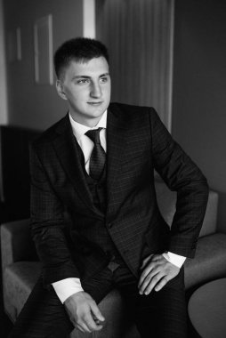 Düğün günü otelde kravatlı, mavi takım elbiseli bir damat portresi.