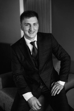 Düğün günü otelde kravatlı, mavi takım elbiseli bir damat portresi.