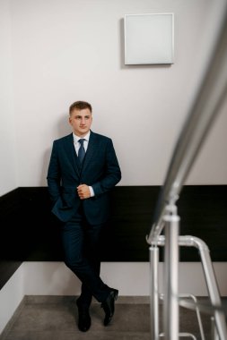 Düğün günü otelde kravatlı, mavi takım elbiseli bir damat portresi.