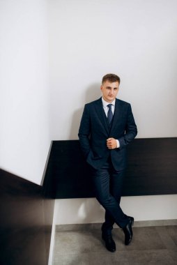 Düğün günü otelde kravatlı, mavi takım elbiseli bir damat portresi.