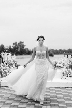 Gelin, sarı bir günbatımının arka planında nehir kıyısındaki bir iskelede