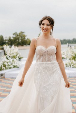 Gelin, sarı bir günbatımının arka planında nehir kıyısındaki bir iskelede