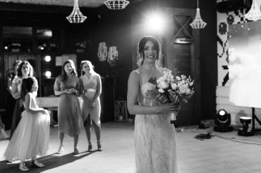 bride in a white dress throws a wedding bouquet to her unmarried girlfriends
