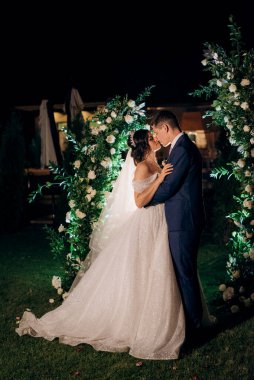 Kız ve erkek, düğün kemerinin arka planında gelin ve damat olarak.