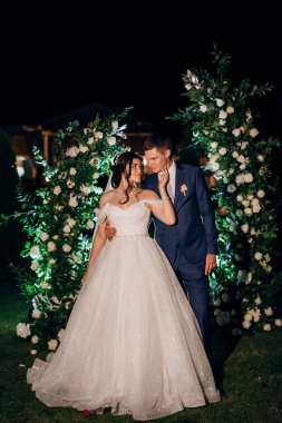 Kız ve erkek, düğün kemerinin arka planında gelin ve damat olarak.