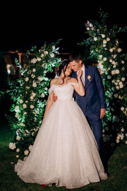 Kız ve erkek, düğün kemerinin arka planında gelin ve damat olarak.