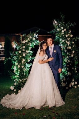 Kız ve erkek, düğün kemerinin arka planında gelin ve damat olarak.