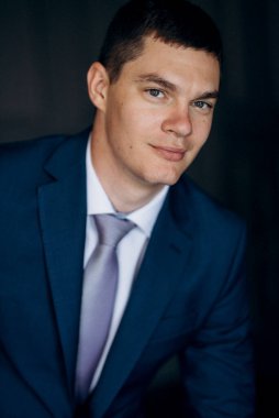 Düğün günü otelde kravatlı, mavi takım elbiseli bir damat portresi.