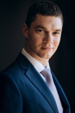 Düğün günü otelde kravatlı, mavi takım elbiseli bir damat portresi.