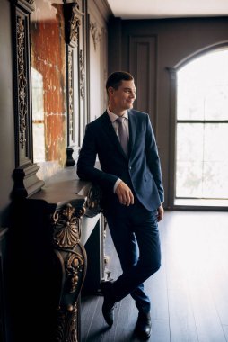 Düğün günü otelde kravatlı, mavi takım elbiseli bir damat portresi.