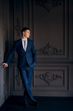 Düğün günü otelde kravatlı, mavi takım elbiseli bir damat portresi.