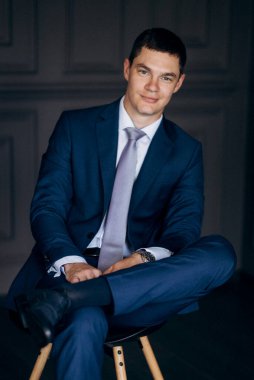 Düğün günü otelde kravatlı, mavi takım elbiseli bir damat portresi.