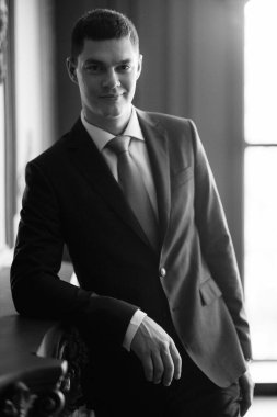 Düğün günü otelde kravatlı, mavi takım elbiseli bir damat portresi.