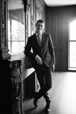 Düğün günü otelde kravatlı, mavi takım elbiseli bir damat portresi.