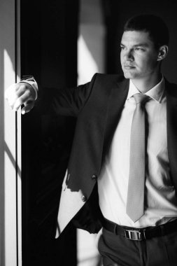 Düğün günü otelde kravatlı, mavi takım elbiseli bir damat portresi.