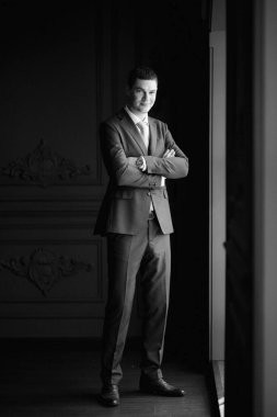 Düğün günü otelde kravatlı, mavi takım elbiseli bir damat portresi.