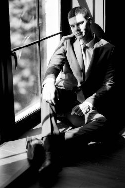 Düğün günü otelde kravatlı, mavi takım elbiseli bir damat portresi.