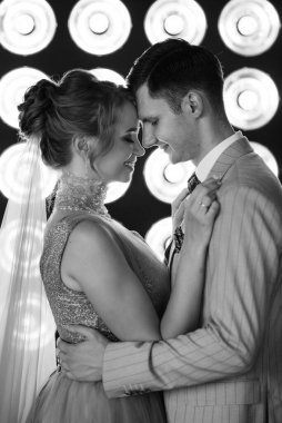 Bej takım elbiseli damat ve lavantalı gelin parlak stüdyoda dar bir gelinlik.