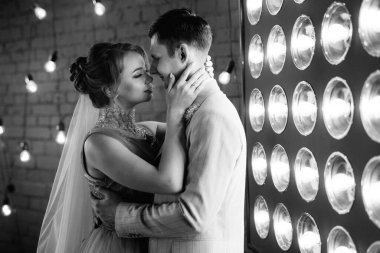 Bej takım elbiseli damat ve lavantalı gelin parlak stüdyoda dar bir gelinlik.