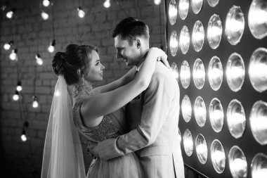 Bej takım elbiseli damat ve lavantalı gelin parlak stüdyoda dar bir gelinlik.