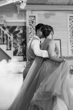 the first dance of the bride and groom inside a restaurant with heavy smoke