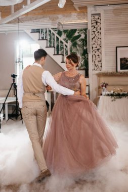 the first dance of the bride and groom inside a restaurant with heavy smoke