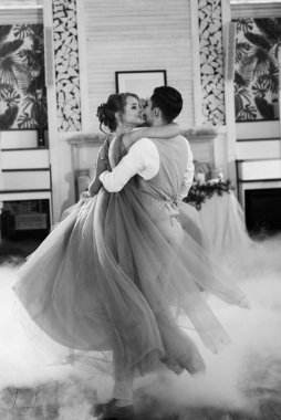 the first dance of the bride and groom inside a restaurant with heavy smoke