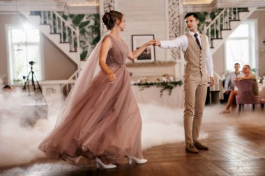 the first dance of the bride and groom inside a restaurant with heavy smoke