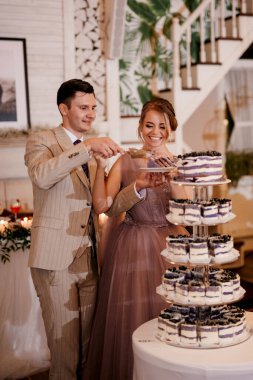newlyweds happily cut, laugh and taste the wedding cake