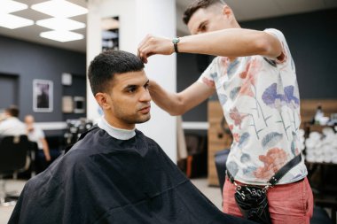 Beyefendinin berber dükkanında sakalını kesen sakallı adam.