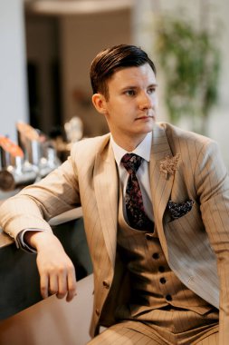 Bej takım elbiseli damadın portresi, parlak bardaki aynalı kravat.