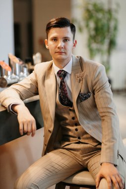 Bej takım elbiseli damadın portresi, parlak bardaki aynalı kravat.