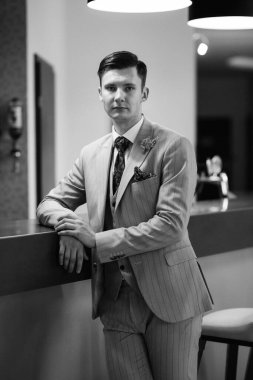 Bej takım elbiseli damadın portresi, parlak bardaki aynalı kravat.