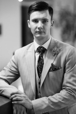 Bej takım elbiseli damadın portresi, parlak bardaki aynalı kravat.