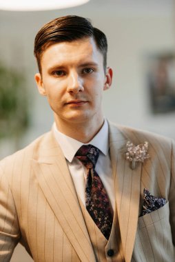 Bej takım elbiseli damadın portresi, parlak bardaki aynalı kravat.