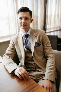 Bej takım elbiseli damadın portresi, parlak bardaki aynalı kravat.