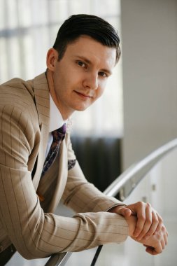 Bej takım elbiseli damadın portresi, parlak bardaki aynalı kravat.