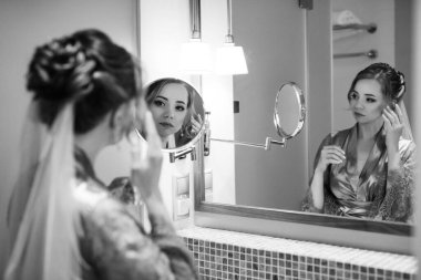 bride in a veil with makeup paints her lips in the bathroom