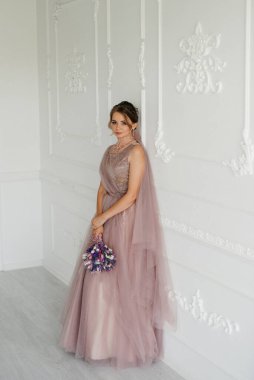 Gelin lavanta renkli pofuduk gelinlik içinde parlak bir stüdyoda buketle