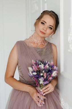 Gelin lavanta renkli pofuduk gelinlik içinde parlak bir stüdyoda buketle